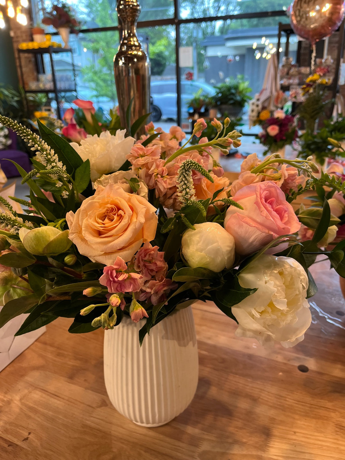 Peach, blush and white flowers in a ribbed cream vase at SoBro Flower Co.