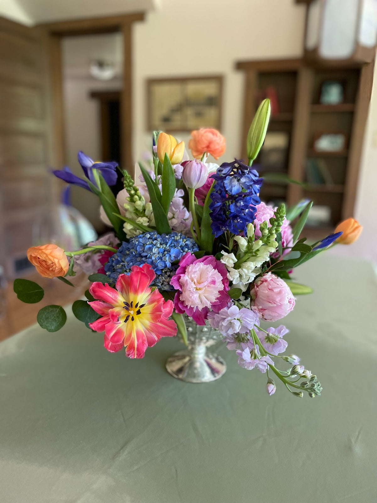 Colorful mixed flowers in a vase, including blue, pink, peach and purple blooms.