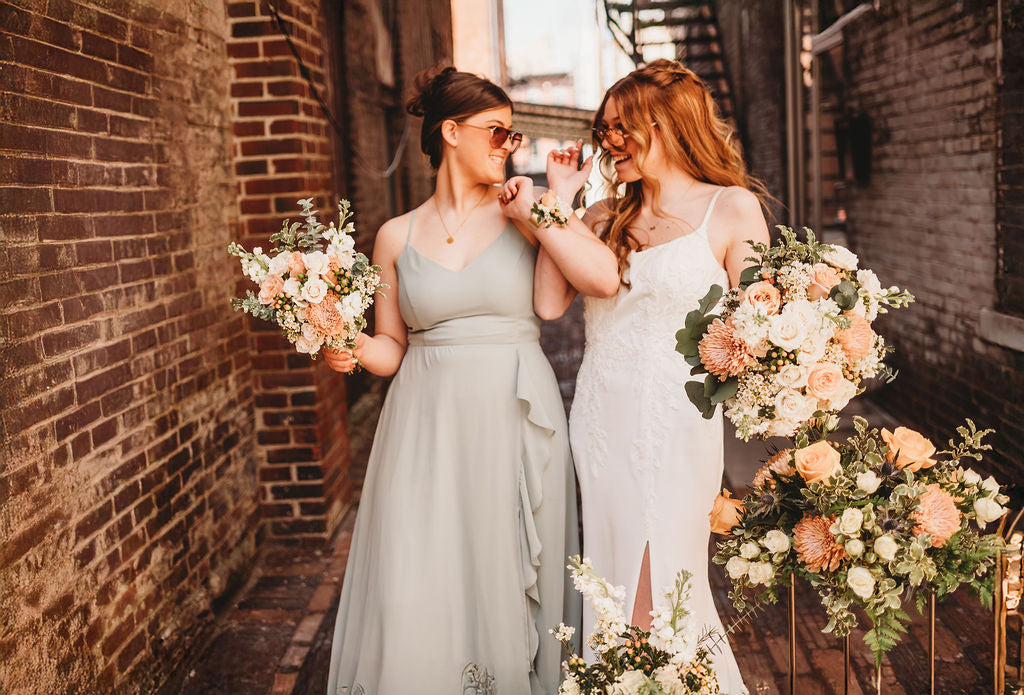 Bride and attendant laughing with peach wedding bouquets