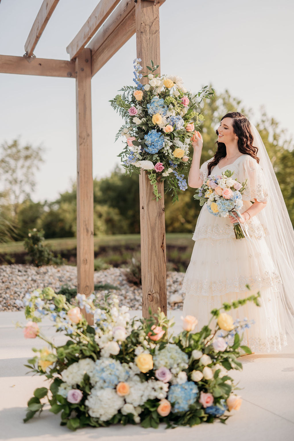 Bride beside a colorful floral ceremony arch