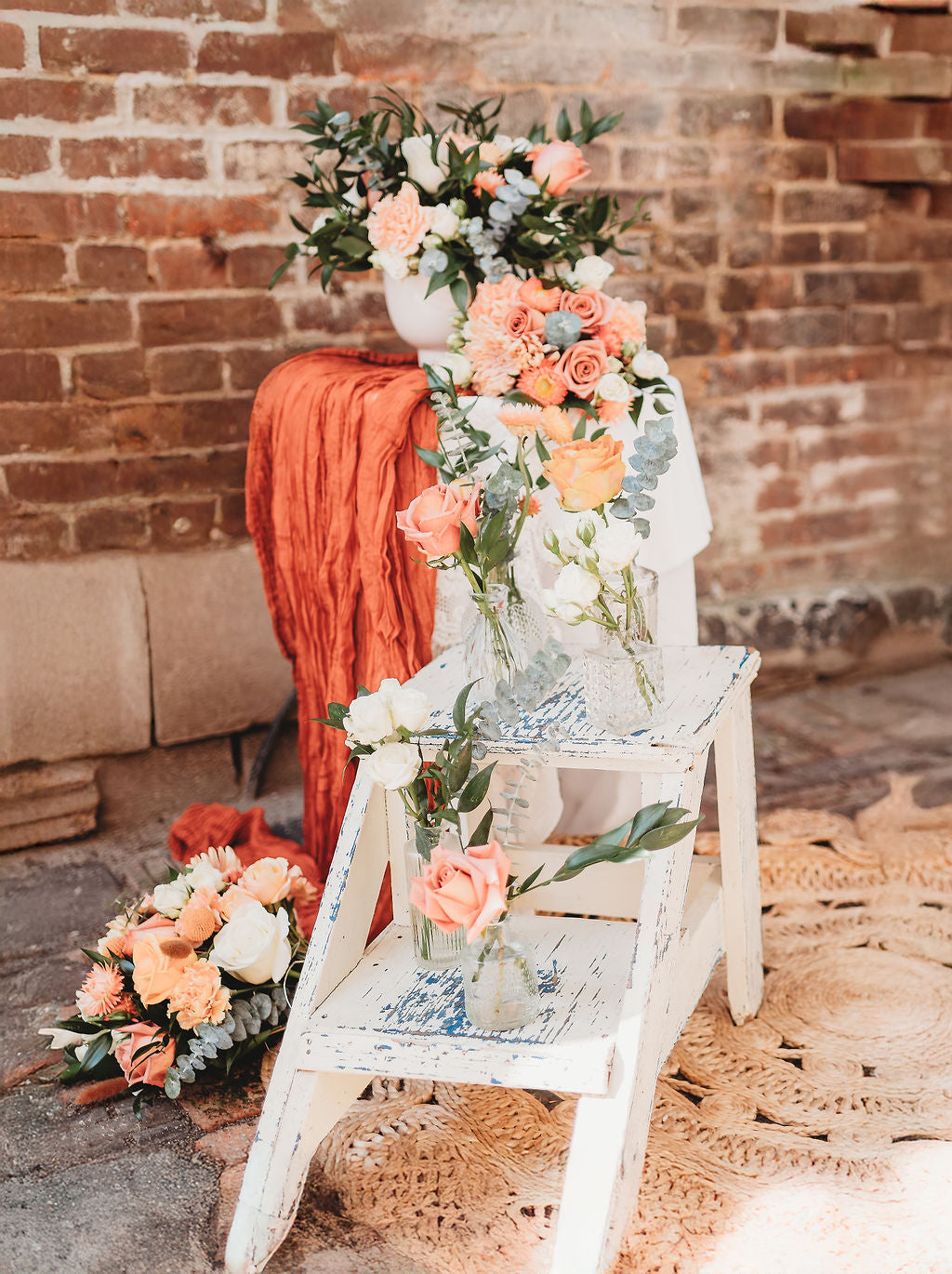 Peach wedding floral installation styled against brick