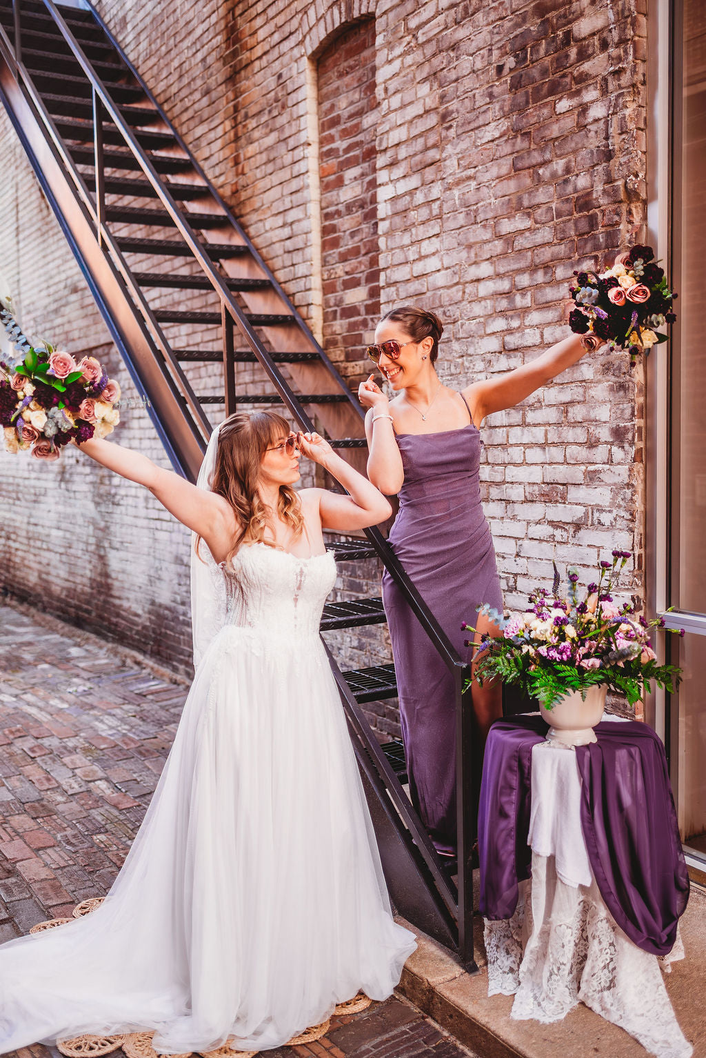 Bride and attendant celebrating with purple wedding flowers