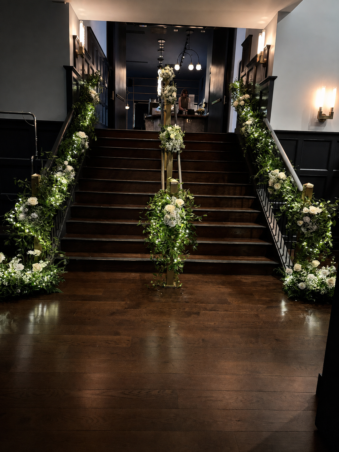White flowers and greenery installed along a staircase by 21 Petals for Purdue graduation at the Union Club Hotel