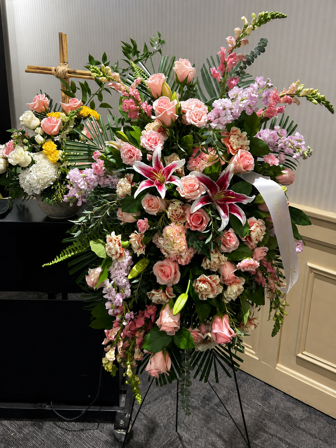 Pink standing sympathy spray with roses, lilies and greenery designed by 21 Petals