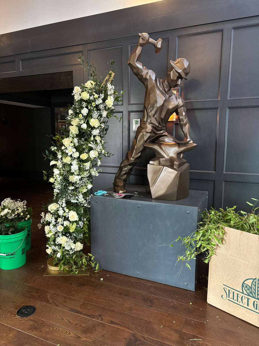 A white floral installation in progress beside a sculpture at the Purdue Union Club Hotel
